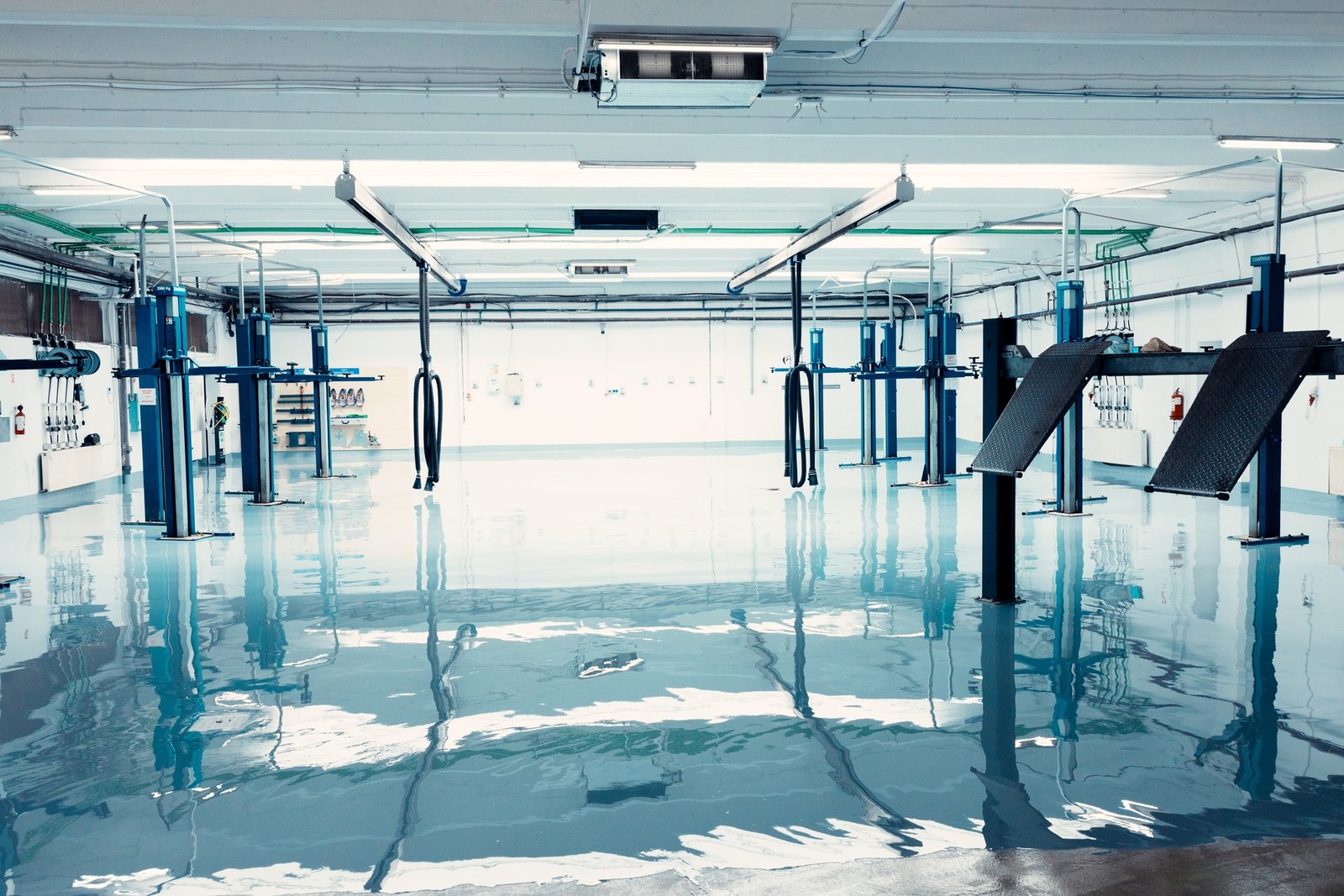 Empty car repair garage with hydraulic lifts and shiny epoxy floor