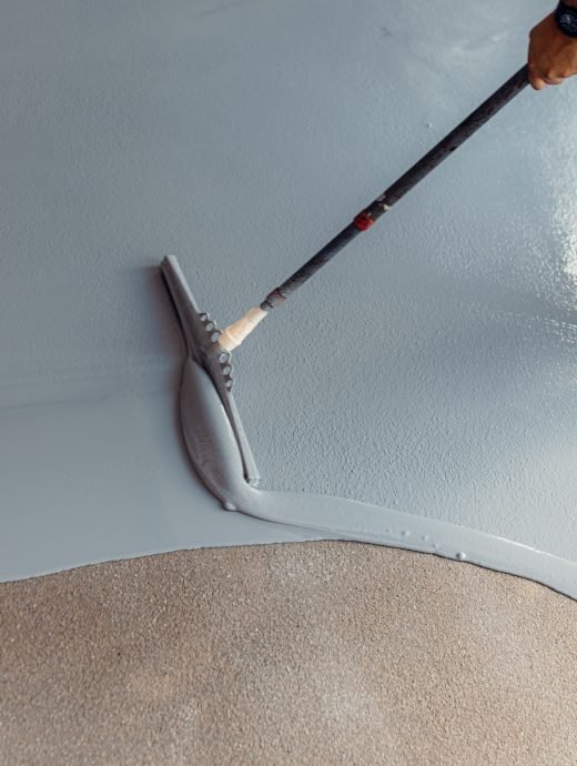 A construction worker apply grey epoxy resin in an industrial hall A construction worker apply grey epoxy resin in an industrial hall